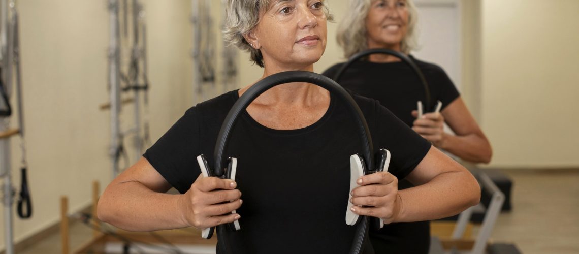mulheres-seniores-de-tiro-medio-em-classe-de-reformador-de-pilates-min