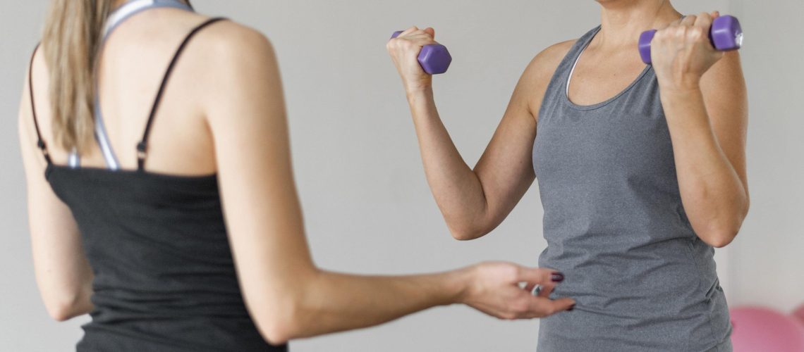 treino-com-personal-trainer-usando-halteres-violetas-min